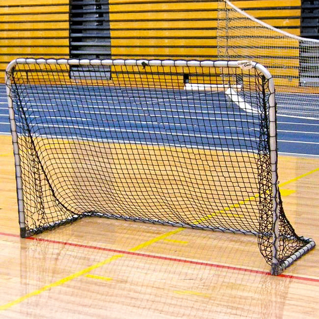 A Folding Aluminum Soccer Goal with a black net and metal frame is set up on a gym floor marked by yellow and red lines, with blue running tracks and yellow bleachers visible in the background.
