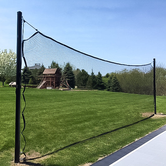 Backyard Backup Netting Systems, designed for volleyball or badminton, is set up on a grassy lawn near a paved area with trees and a wooden play structure in the background under a clear blue sky. Weather-resistant for outdoor use.