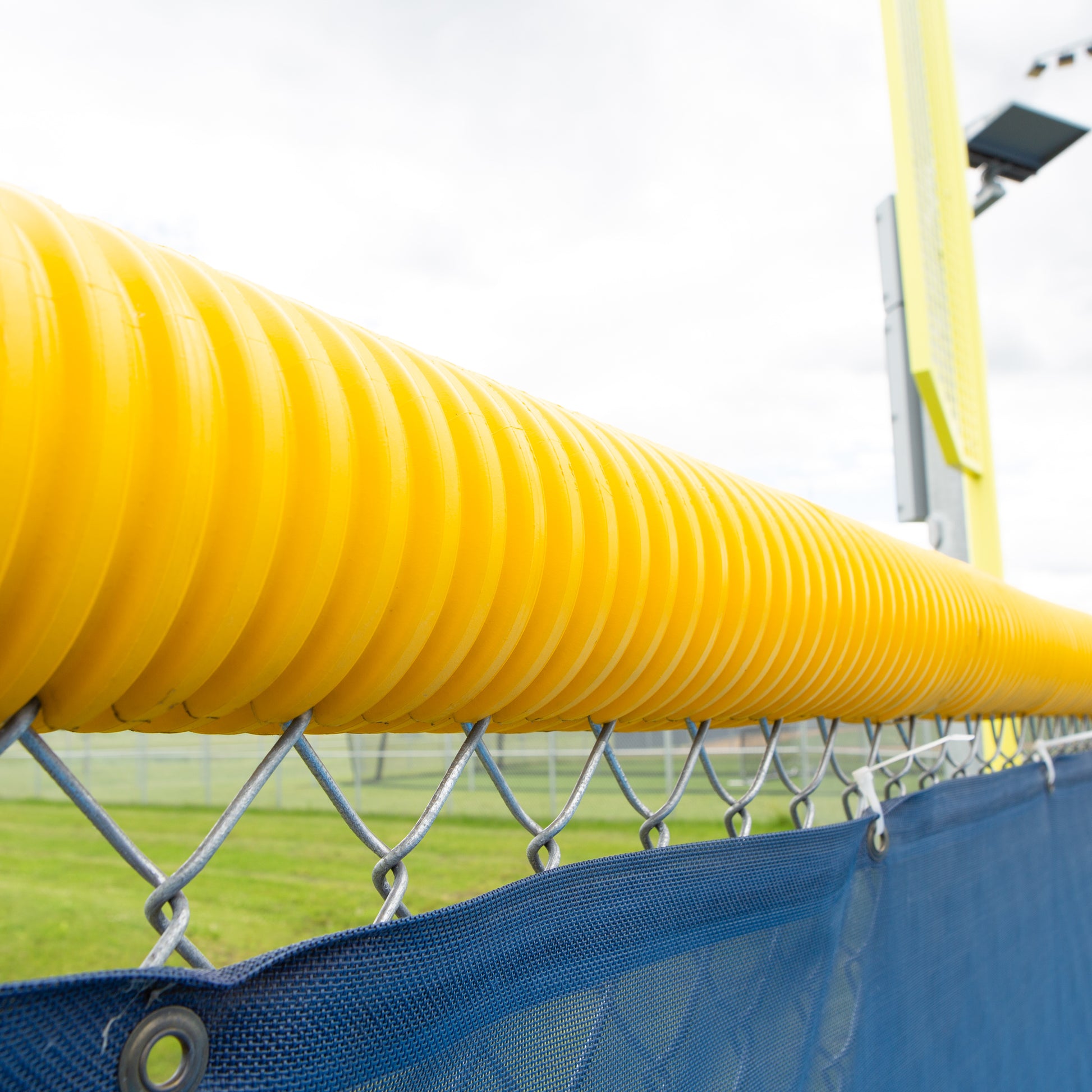 Model #FCECON. Yellow economy fence cap on baseball outfield fence.