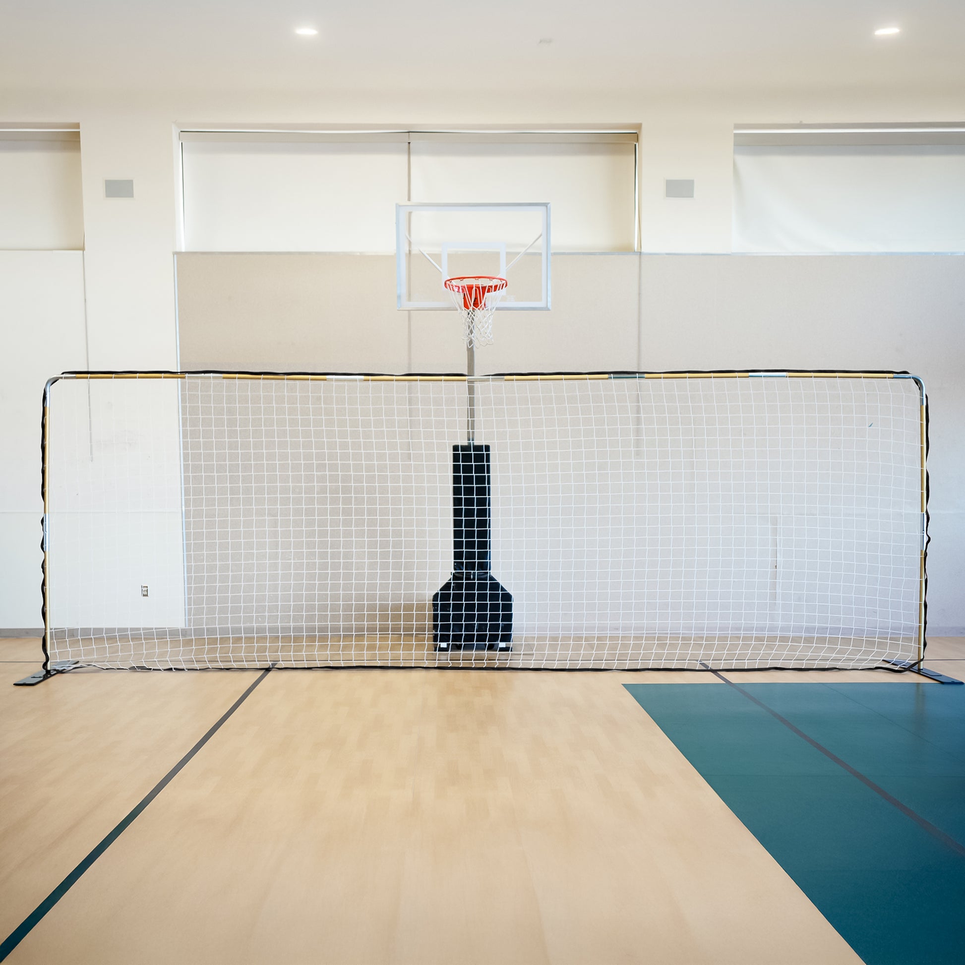 The FFIT Flat Soccer Goal (For Indoor/Turf) is set up in front of a basketball hoop on an indoor gymnasium court with light wood flooring and white walls.