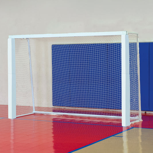 A Bison Official Indoor Futsal Goal with net is set on a red and tan gym floor, backed by a blue padded wall—ideal for indoor games.