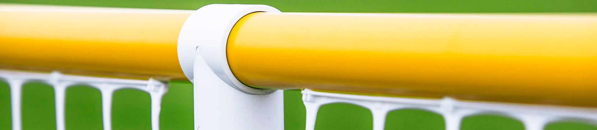 Close-up of a yellow horizontal bar attached to a white post with white netting below, set against a blurred green background.
