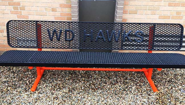Model #PPS9346LIOPP3. School branded 8' black and orange buddy bench outside of school.
