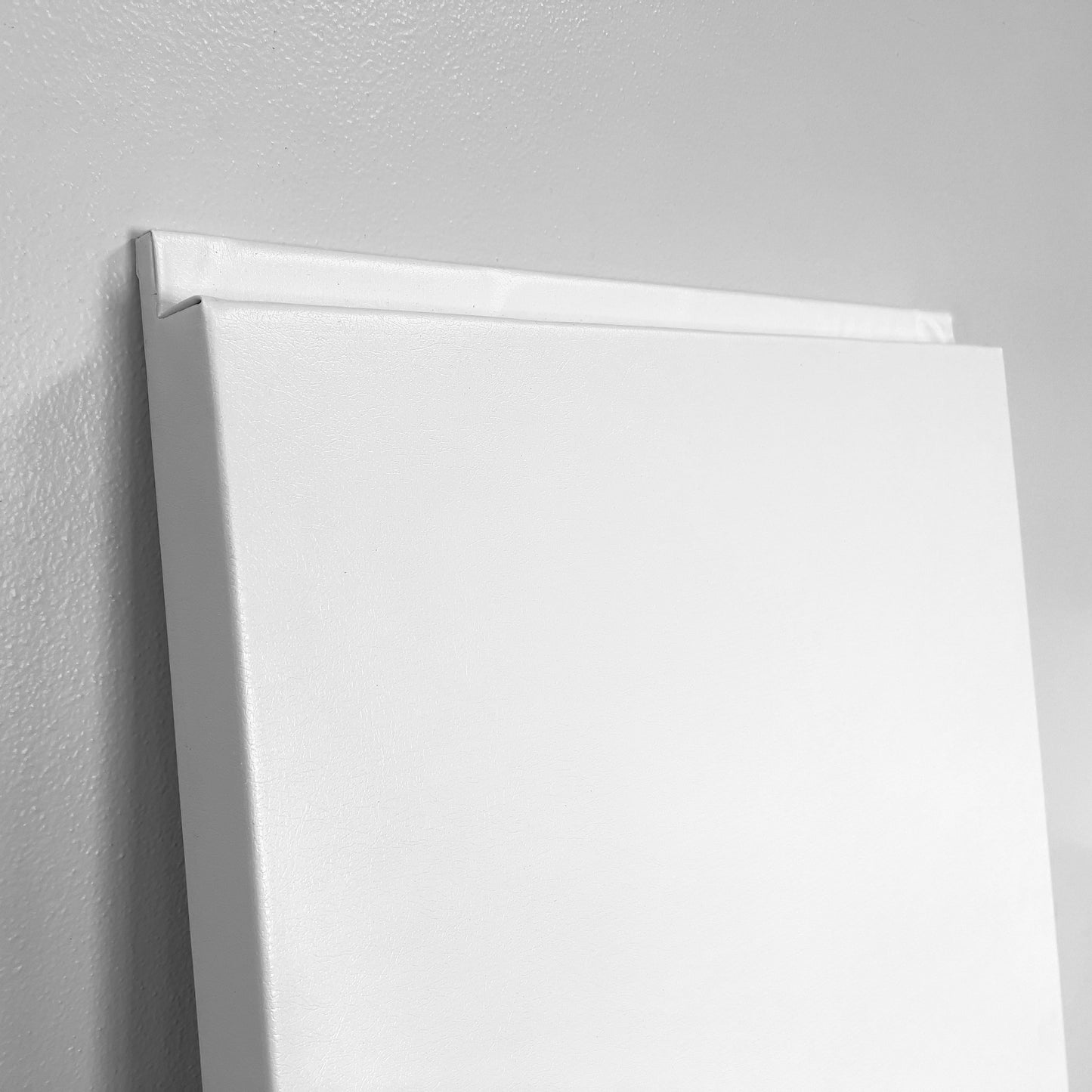 A Wall Pad with wrapped edges and durable poly-foam construction is propped against a light gray wall, displayed from an angled side view.