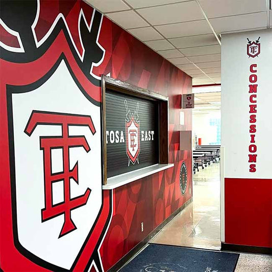 Red, white and black branding graphics on concession stand roll up door and wall.