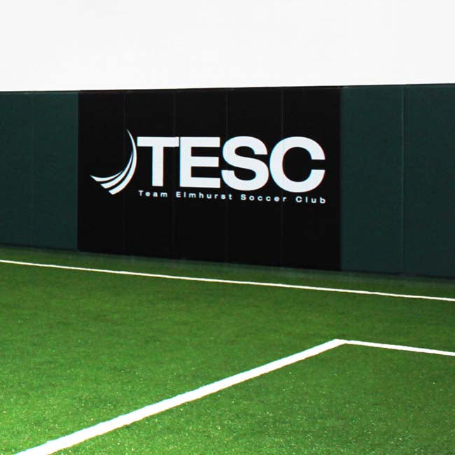 Wall pads with custom logo for indoor soccer facility. Forest green and black.