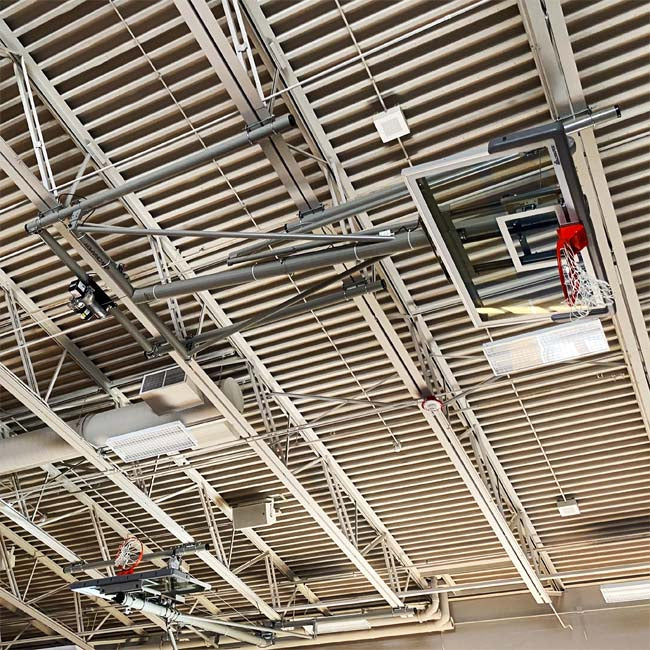 Ceiling mount basketball hoop in the raised position. In a high school gymnasium.