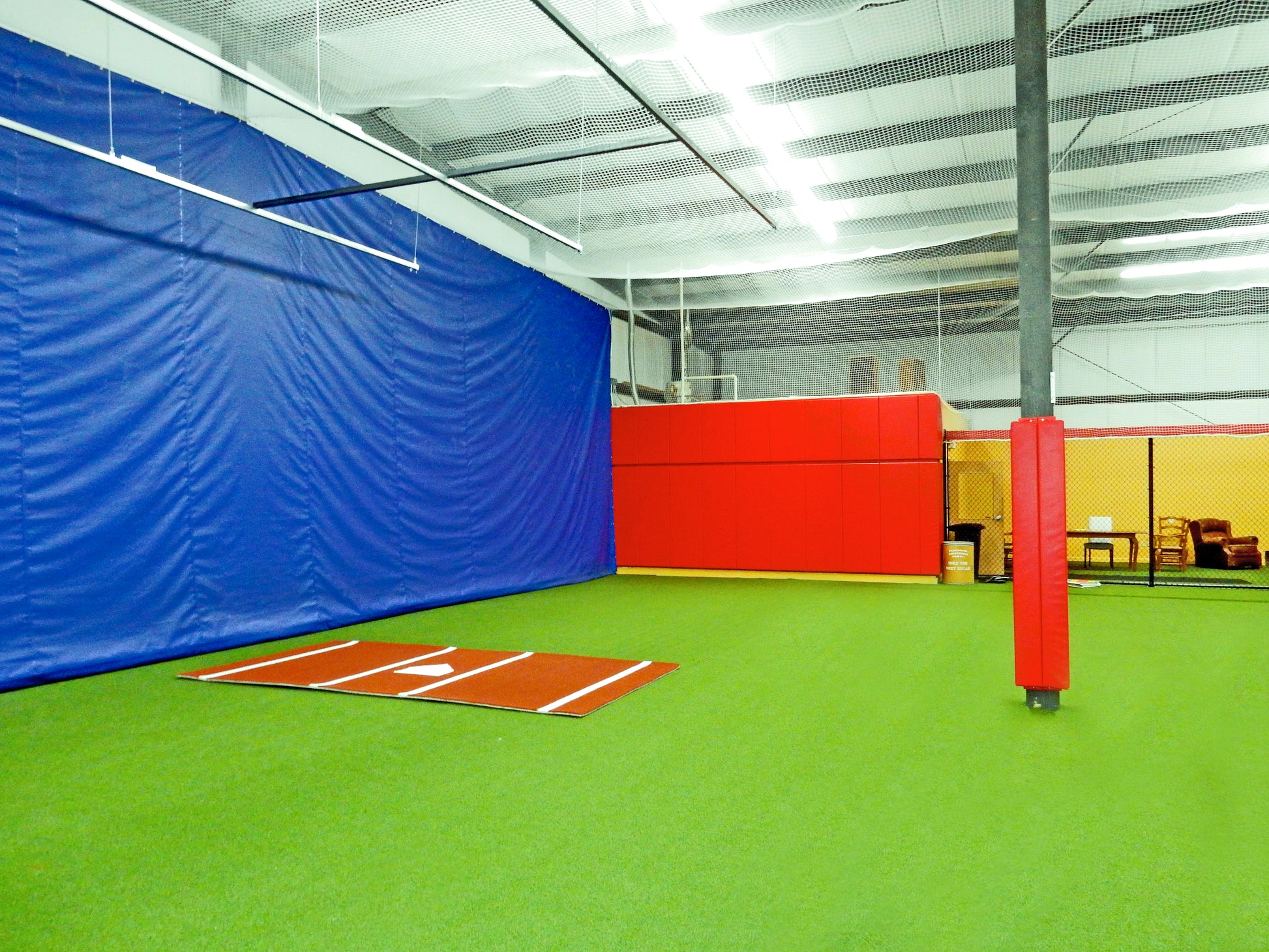 Red padding for wall at indoor baseball facility.
