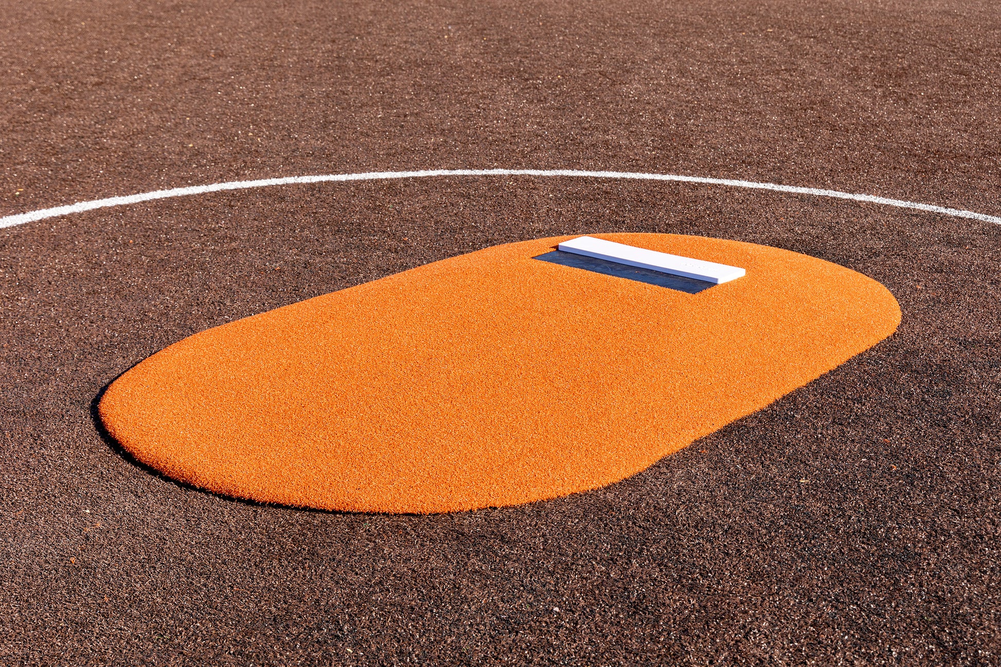 The Portolite 6″ One-Piece Game Mound, designed for ages 8-13, features an orange surface with a white pitcher’s rubber and is pictured on a brown baseball field partially outlined by a white curved line—making it ideal for Little League tournament play.