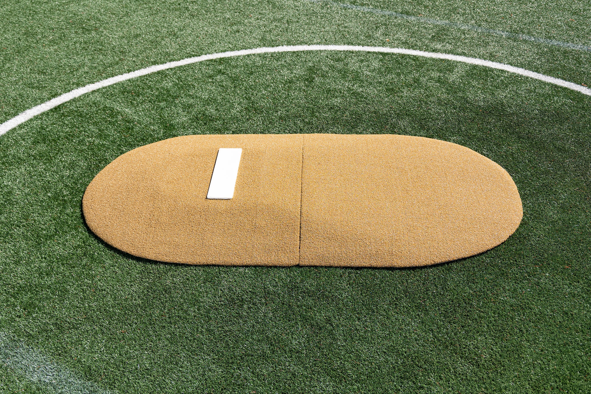 The Portolite 6″ Two-Piece Game Mound for ages 9-13 features a tan oval mound with a white rubber plate, set on green artificial turf and outlined by a white circular boundary—ideal for tournament play as a portable game mound.