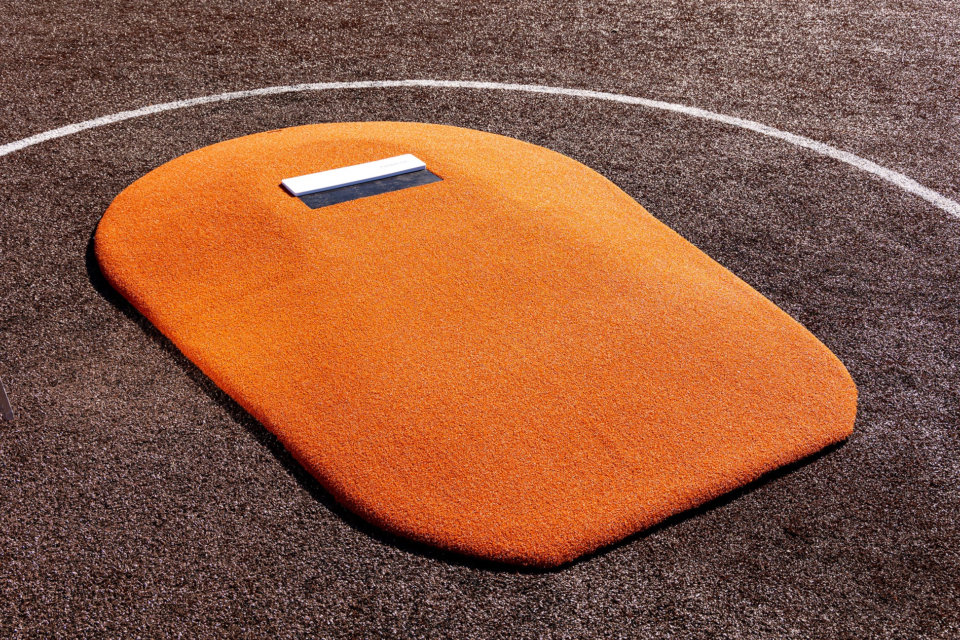 The Portolite 6″ Oversized One-Piece Game Mound, designed for ages 8-13, stands out with its striking orange artificial turf and a white rubber plate on top—ideal for little league players to hone their pitching mechanics. It’s positioned at the center, surrounded by rich brown turf and bordered by a sharp white chalk line.