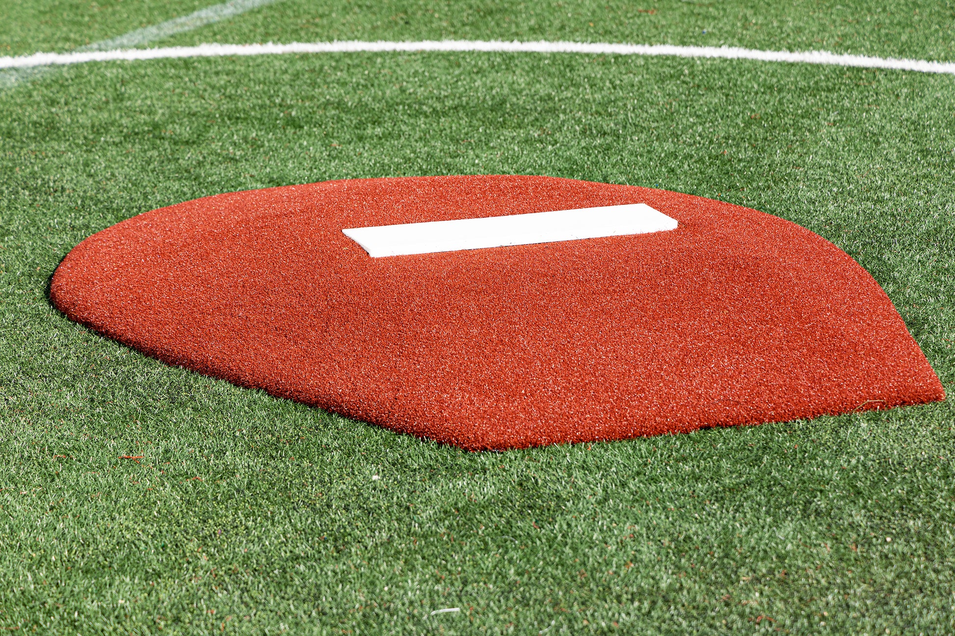 A close-up of the Portolite 6″ Stride Off Game Mound for ages 13 & under, featuring a white pitcher’s plate on top and set on green artificial turf—perfect for Little League and youth pitchers honing their skills.