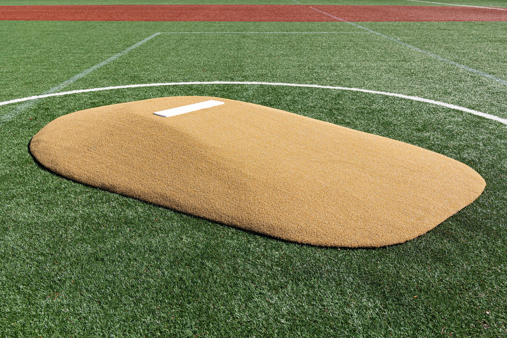 The Portolite 8″ One-Piece Game Mound | Ages 13-15, featuring a tan design with a white rubber plate, is set on green artificial turf accented by white lines and bordered with red turf—perfect for Babe Ruth level games and adaptable for tournaments involving multiple age groups.