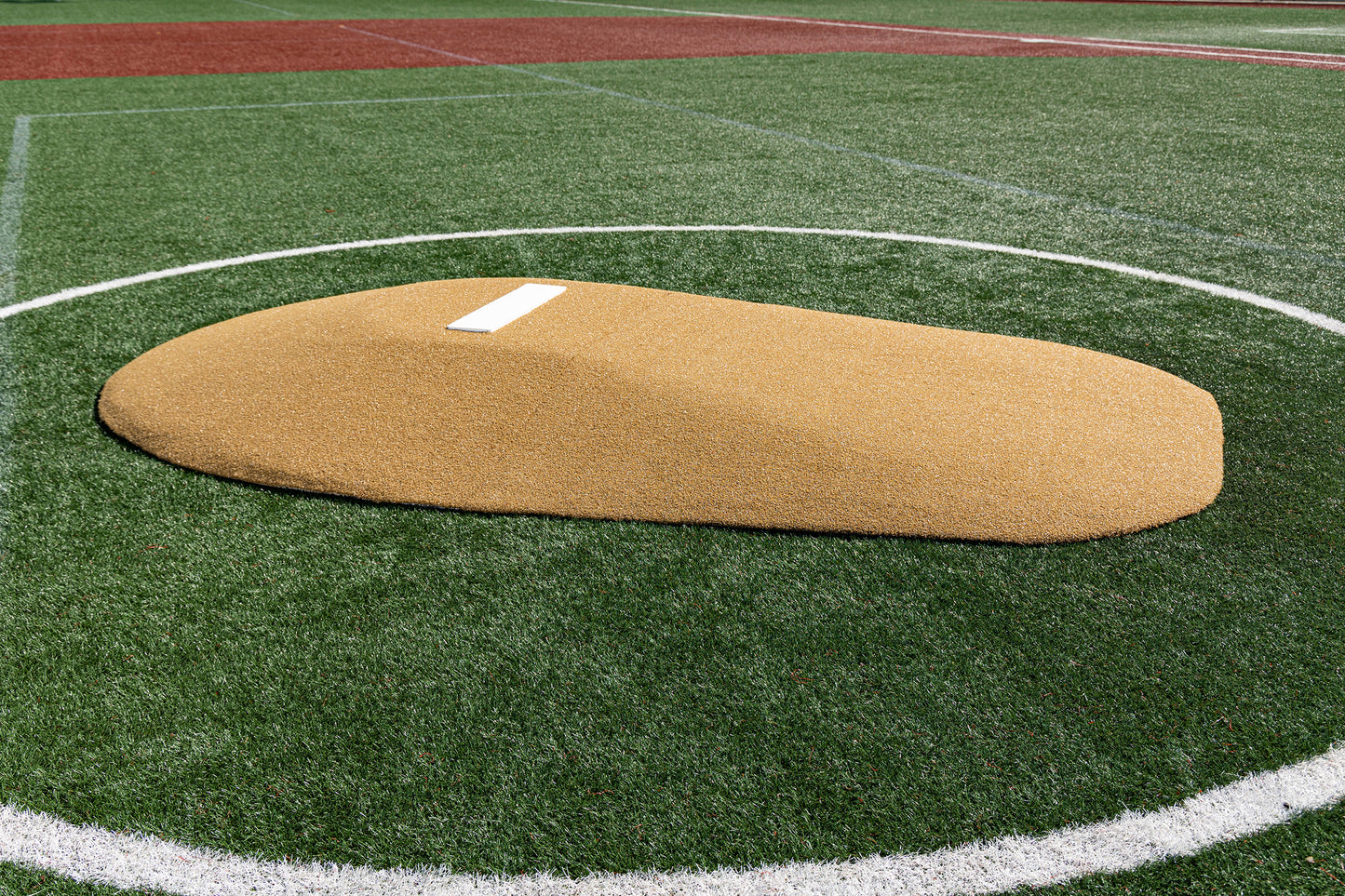 The Portolite 10″ Two-Piece Game Mound | Portable Pitching Mounds, featuring a durable poly core and a white pitching rubber, is set on artificial turf within a white chalk circle on the baseball field, providing the authentic appearance of an AstroTurf mound—perfect for both training and games.