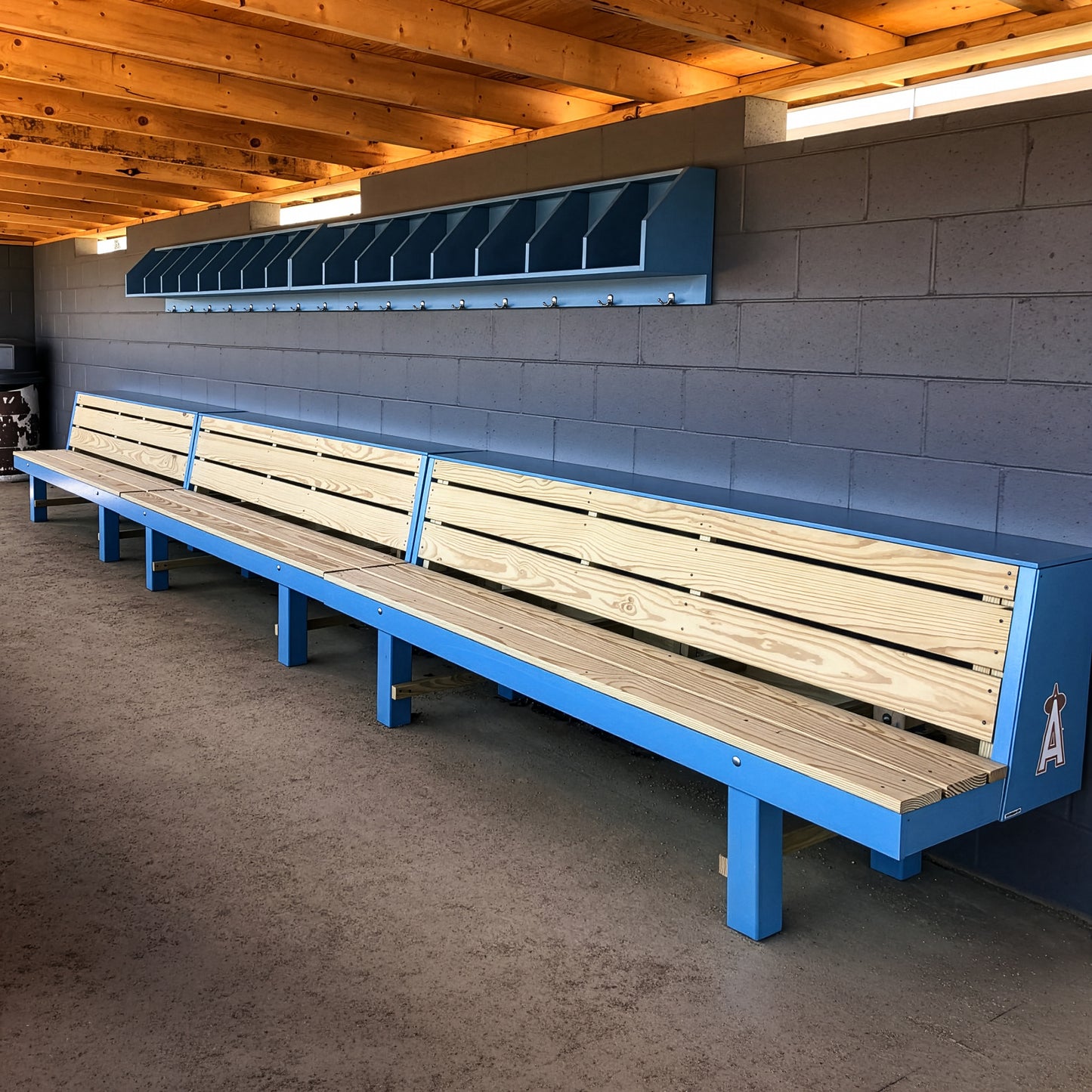 The Condor Baseball & Softball Dugout Bench is a two-tiered wood player bench with a blue frame, cubby shelves, and hooks—ideal for dugout seating in baseball and softball programs.