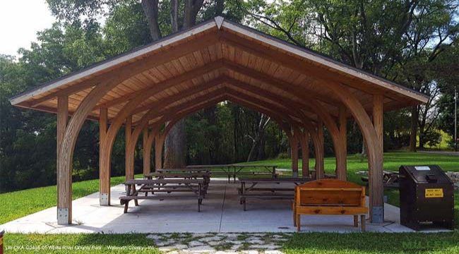 Model #RCPLWOKAG2436. 24'x36' laminated wood open knee arch gable shelter with optional metal roofing.