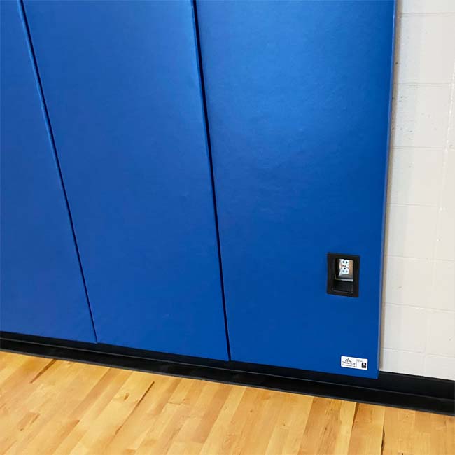 Wall padding in gymnasium with outlet cutout.