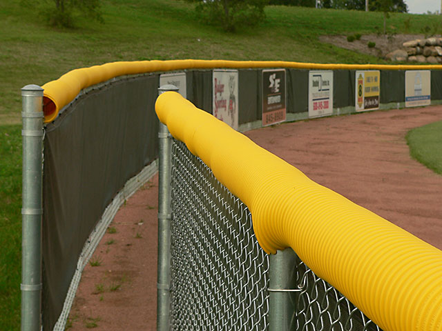 Model #FCECON. Yellow economy fence cap on baseball outfield fence.