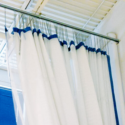 Walk-draw gym divider curtain retracted in white mesh and blue vinyl.
