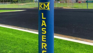 Blue football goal post pad with yellow lettering and school logo.