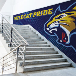 Wildcat Pride vinyl wall wrap in school stairwell. Yellow letters and logo on blue background.