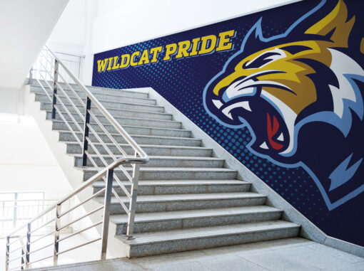 Wildcat Pride vinyl wall wrap in school stairwell. Yellow letters and logo on blue background.