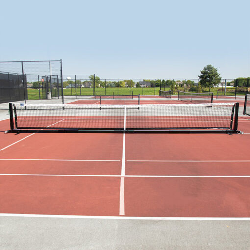 Entire portable pickleball net on pickleball court with other pickleball courts in the background.