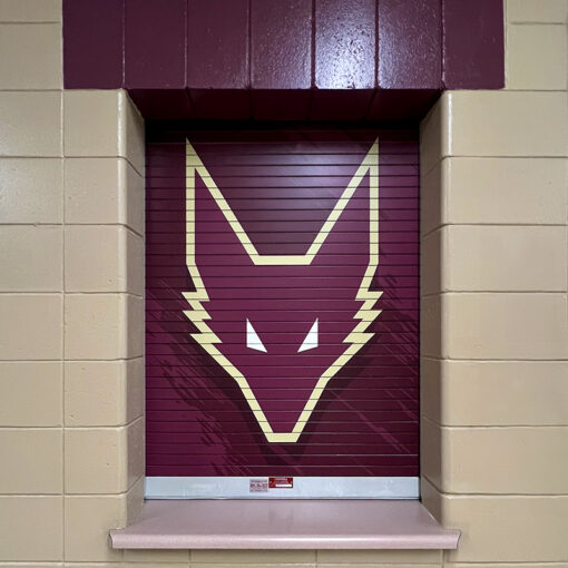 Maroon fox logo with gold outline on roll up concession stand door.