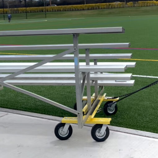 Yellow goal taxi with wheels being used to move portable bleachers.